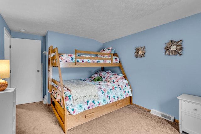 bedroom with vaulted ceiling, light colored carpet, and a textured ceiling