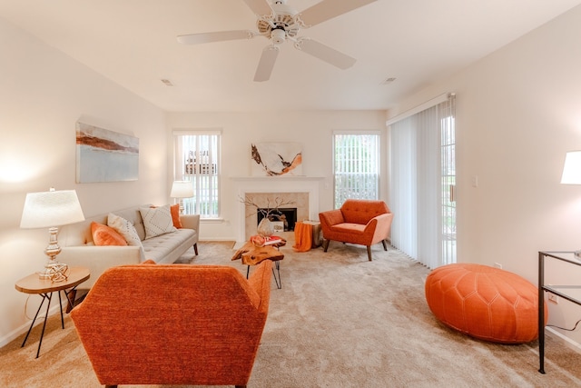 carpeted living room with ceiling fan, a healthy amount of sunlight, and a tile fireplace