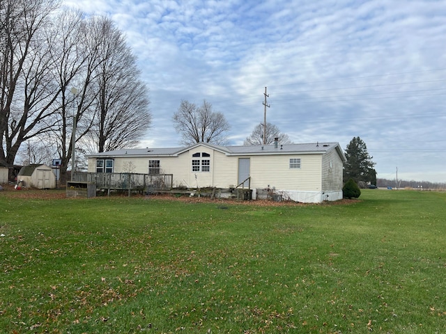 rear view of property with a lawn, a shed, and a deck