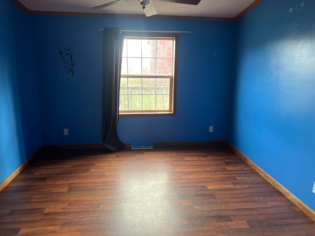 spare room with a textured ceiling, crown molding, ceiling fan, and dark wood-type flooring