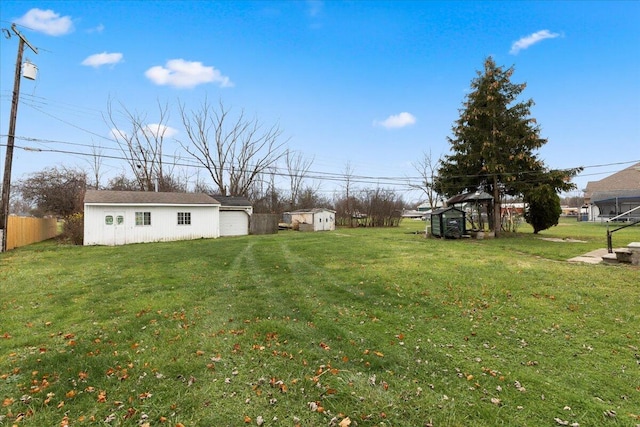 view of yard with an outdoor structure, a storage unit, and fence