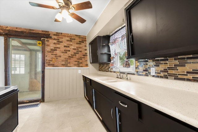 kitchen featuring a wainscoted wall, plenty of natural light, light countertops, and a sink