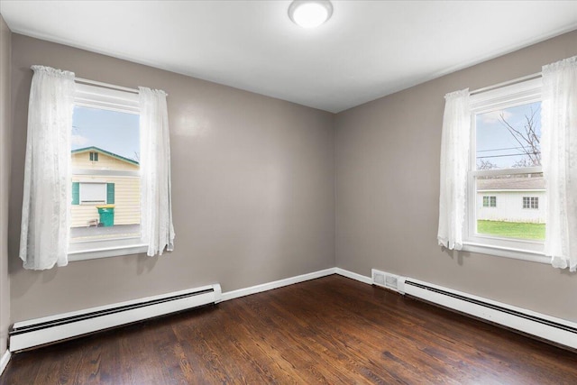 spare room with dark wood-style flooring, baseboard heating, and baseboards