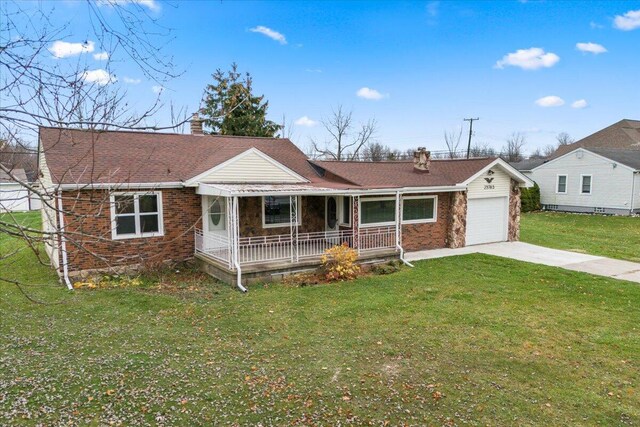 view of front facade with covered porch, brick siding, concrete driveway, a chimney, and a front yard