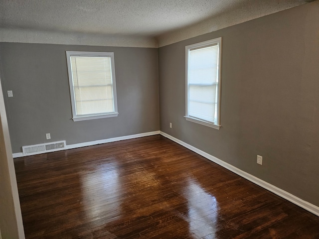 empty room featuring dark hardwood / wood-style floors and a textured ceiling