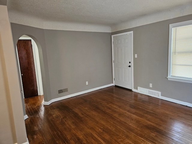 unfurnished room featuring dark wood-type flooring and a textured ceiling