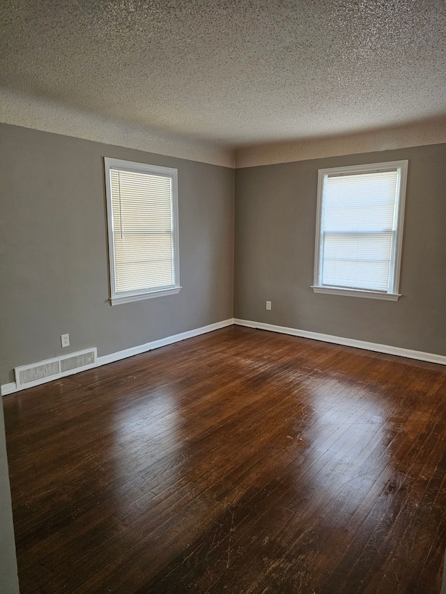 spare room featuring a textured ceiling and dark hardwood / wood-style floors