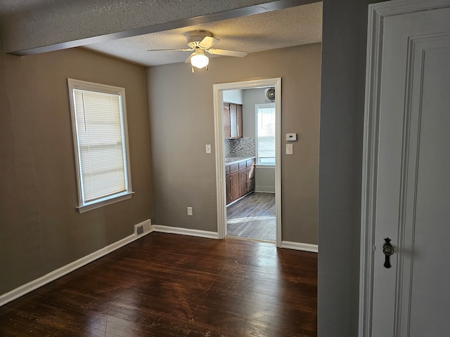 empty room with a textured ceiling, ceiling fan, and dark wood-type flooring