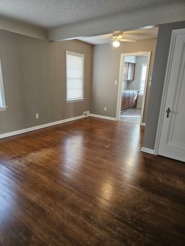 empty room featuring a textured ceiling, dark hardwood / wood-style floors, and ceiling fan