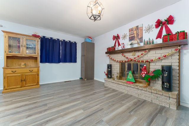 interior space with a brick fireplace, a notable chandelier, and light hardwood / wood-style floors