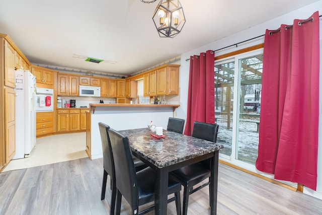 dining room with light hardwood / wood-style floors and a chandelier