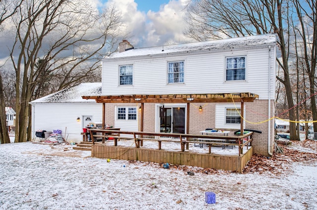 snow covered back of property with a wooden deck