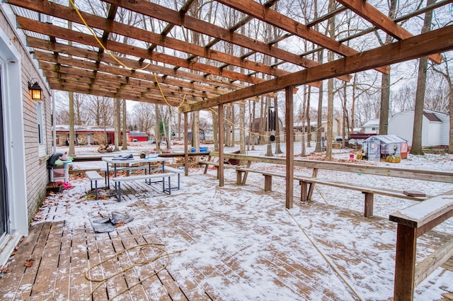 snow covered deck featuring a shed and a pergola