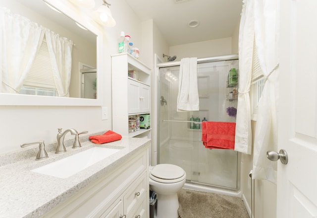 bathroom featuring toilet, a shower with door, and vanity