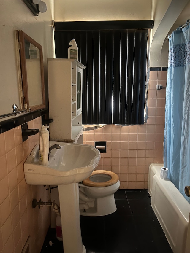 bathroom with tile patterned flooring, shower / bath combo, tile walls, and toilet