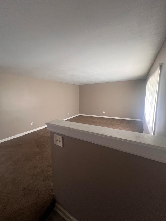 unfurnished room featuring dark colored carpet