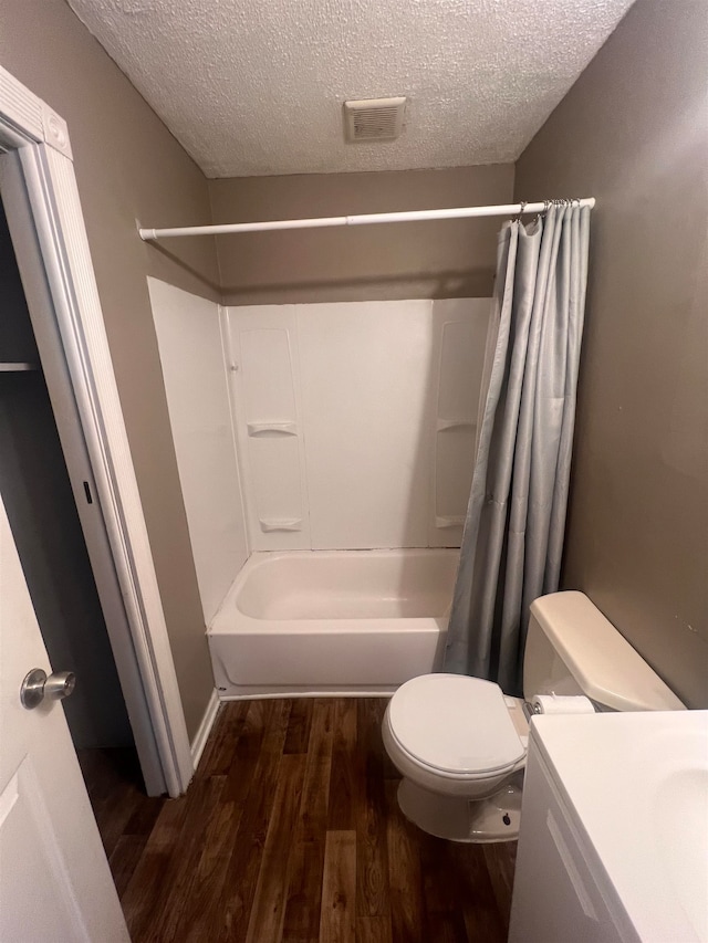 full bathroom featuring hardwood / wood-style floors, shower / bath combo, a textured ceiling, and toilet