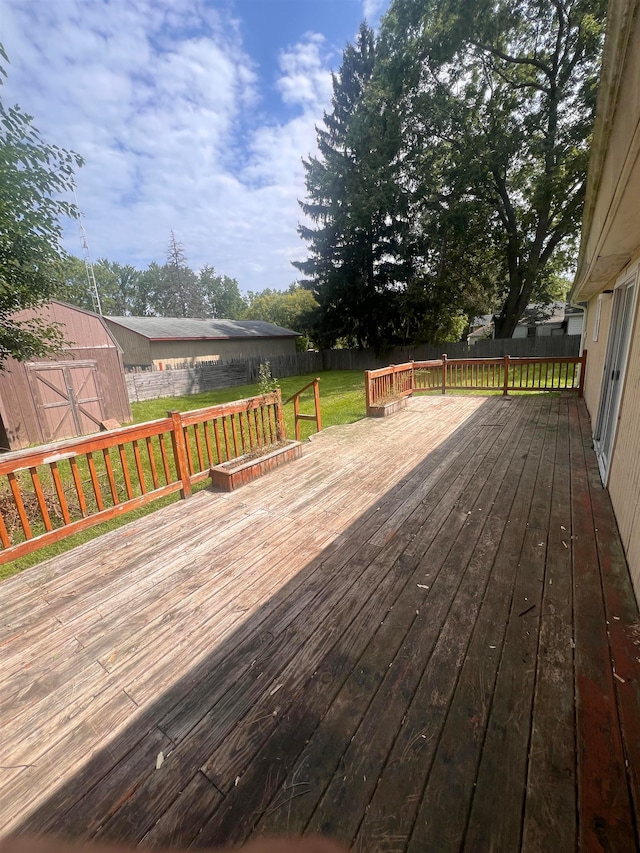 wooden terrace featuring a storage unit and a lawn