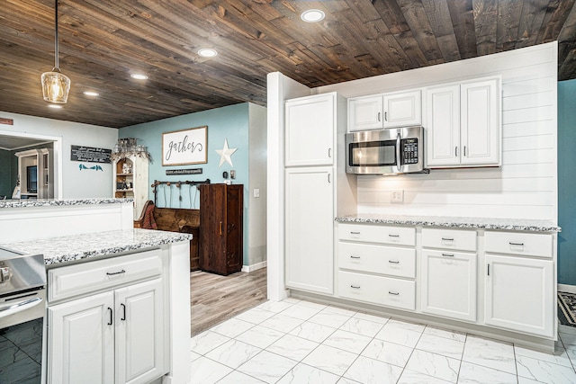 kitchen featuring marble finish floor, white cabinetry, and stainless steel microwave