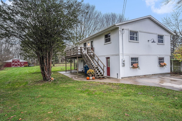 view of home's exterior with an outbuilding, stairway, a wooden deck, and a lawn