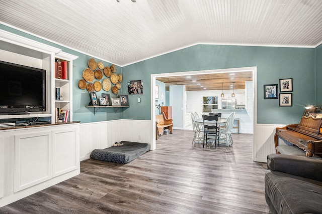 living room with lofted ceiling, ornamental molding, wainscoting, and wood finished floors