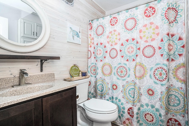 full bath featuring toilet, wooden walls, and vanity