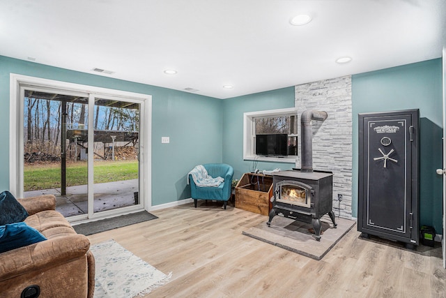 sitting room featuring light wood-type flooring, a wood stove, baseboards, and recessed lighting