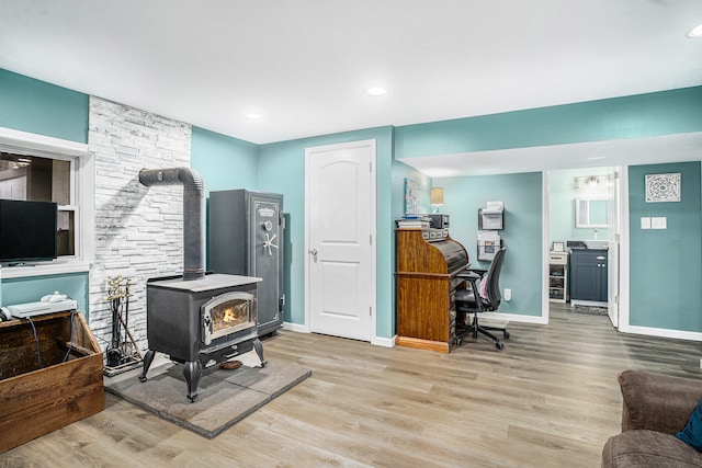 office featuring a wood stove, light wood-style flooring, baseboards, and recessed lighting