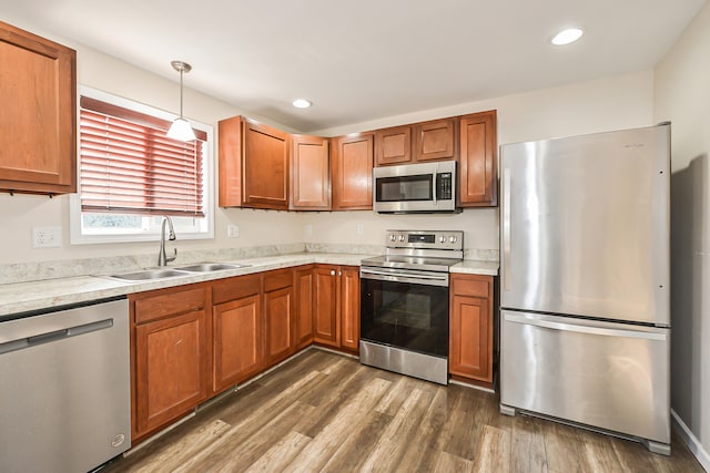 kitchen with appliances with stainless steel finishes, dark hardwood / wood-style flooring, decorative light fixtures, and sink