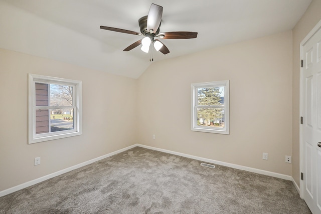 carpeted empty room featuring plenty of natural light, ceiling fan, and lofted ceiling