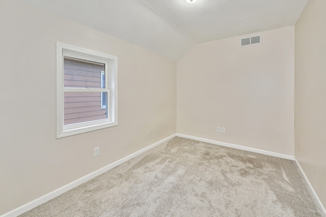 spare room with light colored carpet and lofted ceiling