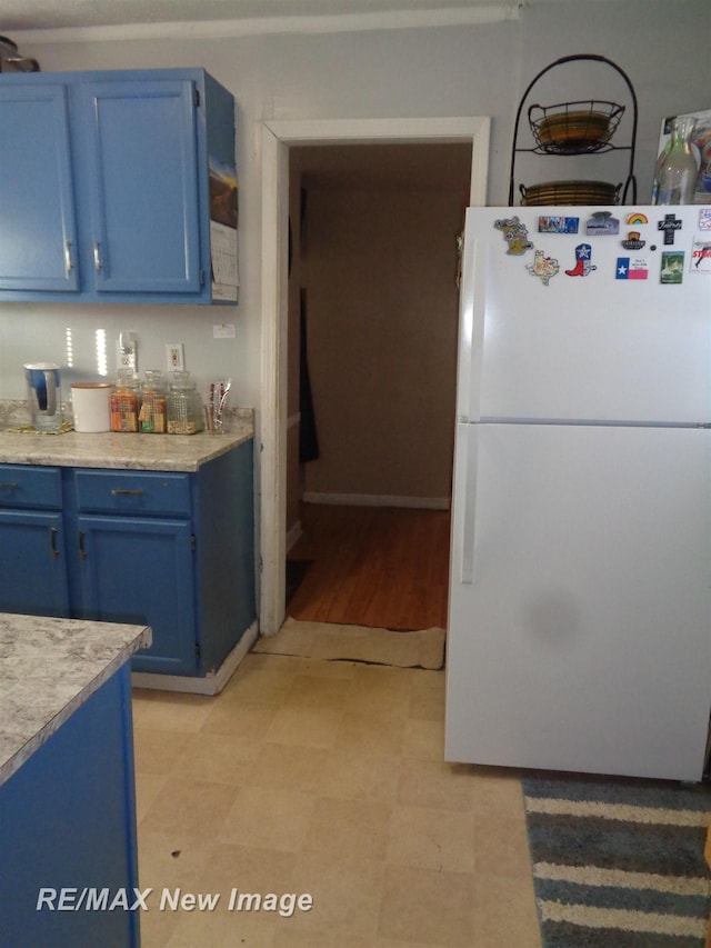 kitchen featuring blue cabinetry, light wood-type flooring, and white refrigerator