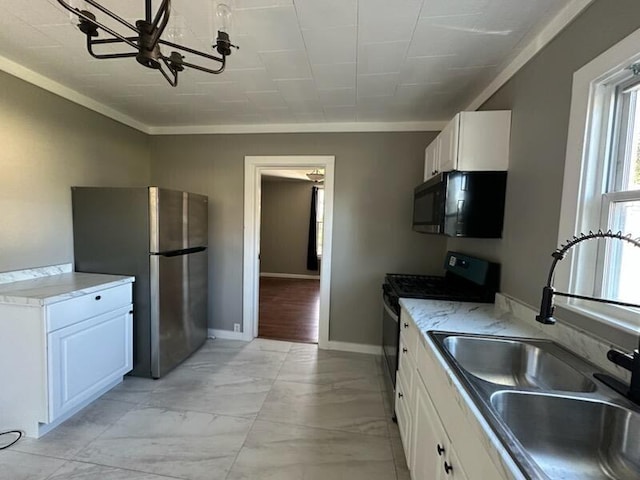 kitchen featuring sink, white cabinets, a notable chandelier, and appliances with stainless steel finishes