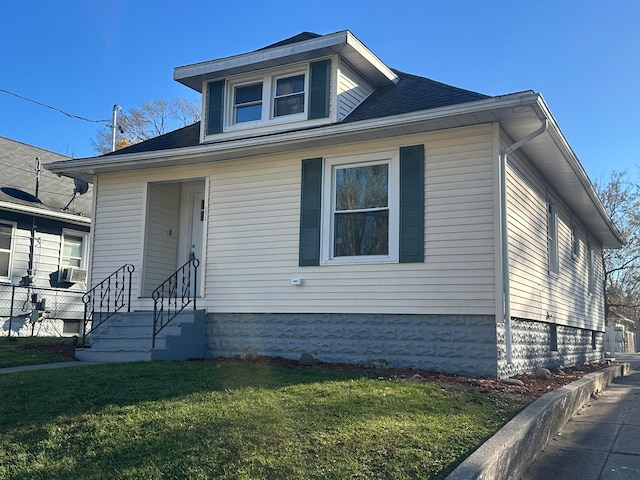 bungalow-style house with cooling unit and a front lawn