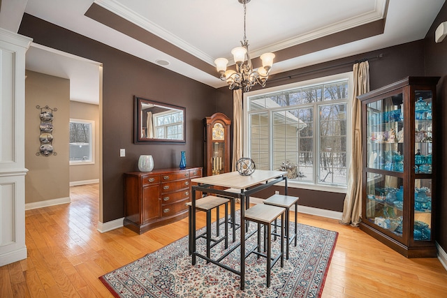 dining room featuring crown molding, baseboards, a tray ceiling, an inviting chandelier, and light wood-style floors