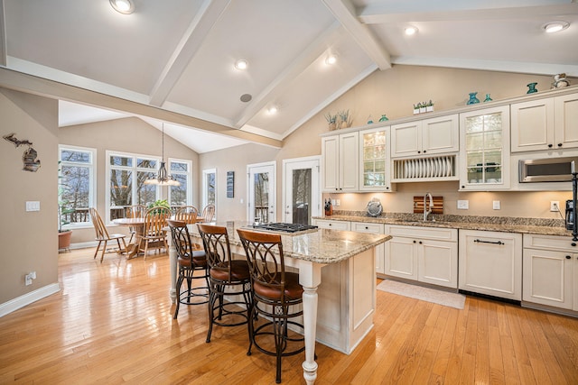 kitchen with a kitchen breakfast bar, decorative light fixtures, light hardwood / wood-style flooring, white cabinets, and a kitchen island