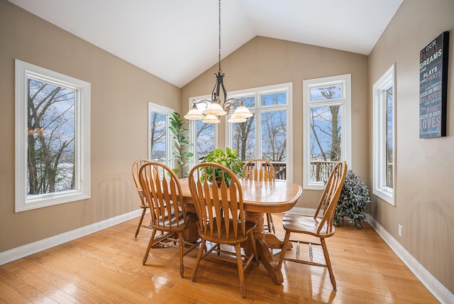 dining space with light wood-style flooring, lofted ceiling, an inviting chandelier, and a healthy amount of sunlight