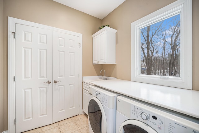 washroom featuring a sink, washing machine and dryer, cabinet space, light tile patterned floors, and a healthy amount of sunlight