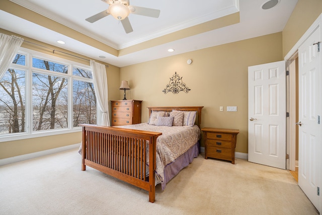 bedroom featuring a raised ceiling, light colored carpet, baseboards, and ornamental molding