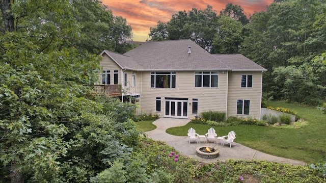 back of house at dusk with a patio, a fire pit, and a yard