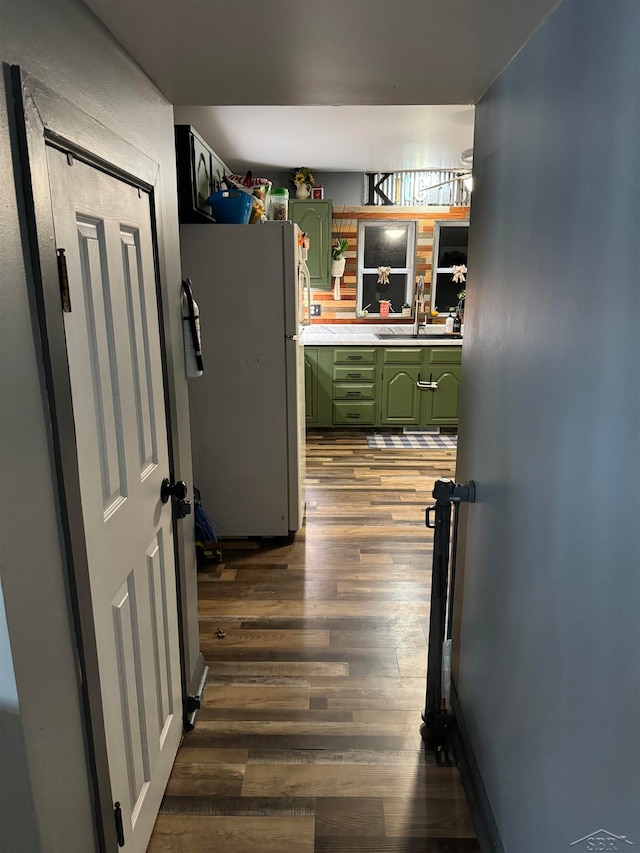 kitchen featuring white fridge, sink, dark wood-type flooring, and green cabinetry