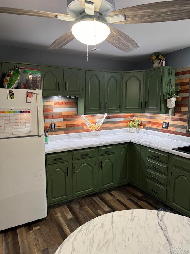 kitchen with white refrigerator, dark hardwood / wood-style flooring, green cabinets, and backsplash