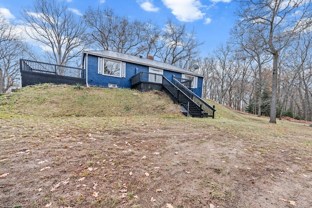 3897 Sand Rd, Port Austin, MI 48467 - view of front of house featuring a deck, a chimney, stairs, and brick siding