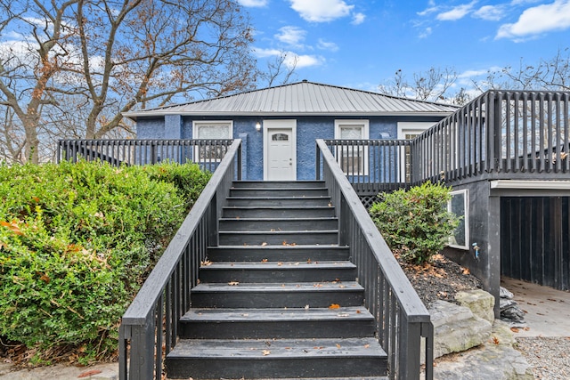 3897 Sand Rd, Port Austin, MI 48467 - view of front facade featuring stairs, metal roof, a deck, and stucco siding