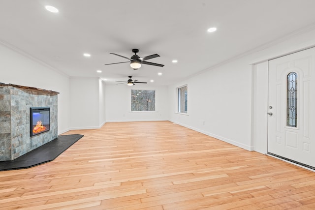 3897 Sand Rd, Port Austin, MI 48467 - unfurnished living room with crown molding, recessed lighting, light wood-style floors, a tiled fireplace, and a ceiling fan