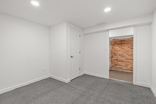3897 Sand Rd, Port Austin, MI 48467 - unfurnished bedroom with dark carpet, brick wall, recessed lighting, and baseboards