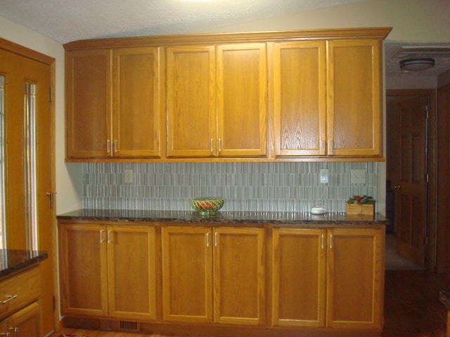 kitchen featuring tasteful backsplash and dark stone countertops