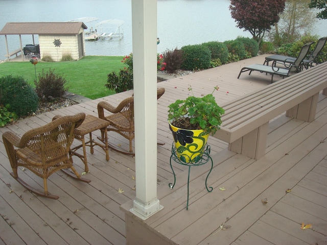 deck featuring an outdoor structure, a water view, and a yard