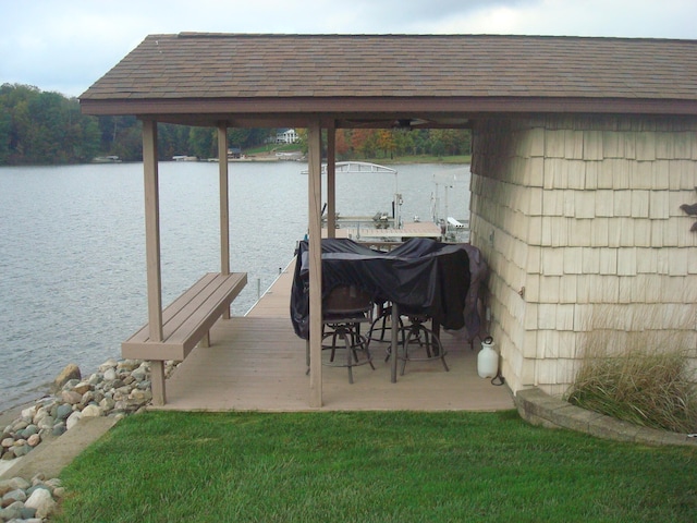 view of dock with a water view and a yard