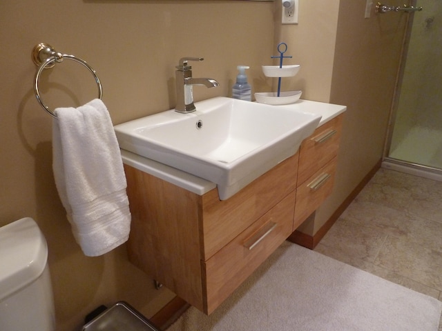 bathroom featuring a shower with door, vanity, and toilet